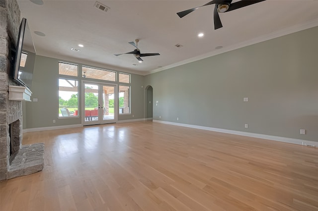 unfurnished living room featuring light hardwood / wood-style flooring, a fireplace, ceiling fan, ornamental molding, and french doors