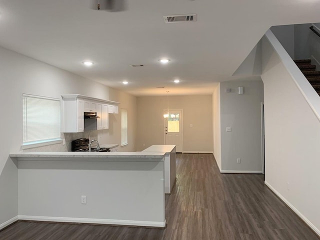 kitchen featuring kitchen peninsula, white cabinets, dark hardwood / wood-style floors, and black range