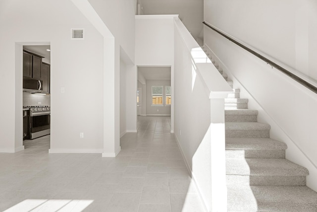 staircase featuring tile patterned flooring and a high ceiling