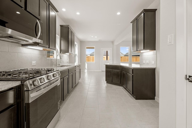 kitchen with light stone countertops, light tile patterned floors, stainless steel appliances, and sink