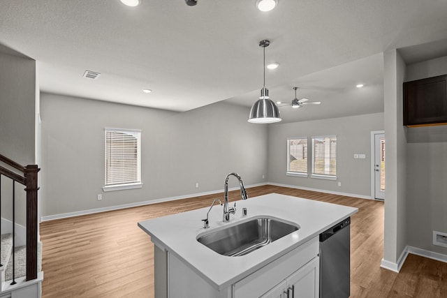 kitchen featuring sink, white cabinetry, hanging light fixtures, an island with sink, and stainless steel dishwasher