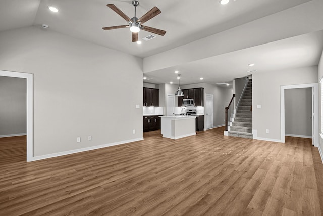 unfurnished living room with sink, wood-type flooring, ceiling fan, and vaulted ceiling