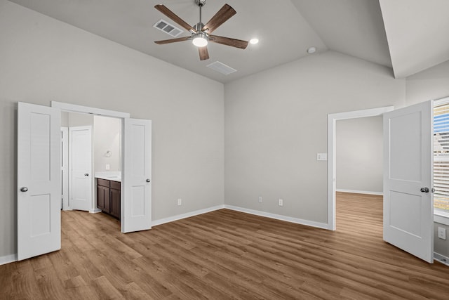 unfurnished bedroom featuring vaulted ceiling, light wood-type flooring, ensuite bathroom, and ceiling fan