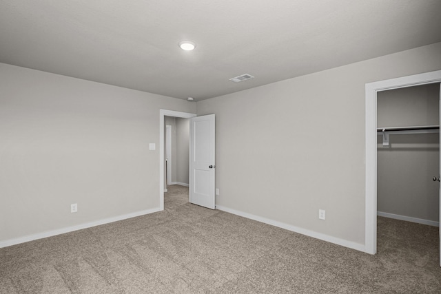 unfurnished bedroom featuring a walk in closet, carpet floors, and a closet