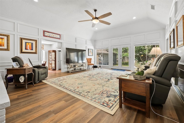 living room with ceiling fan, french doors, hardwood / wood-style floors, lofted ceiling, and a textured ceiling