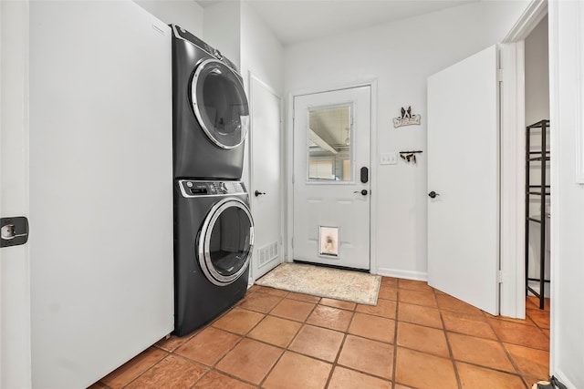 laundry room with stacked washer and dryer and light tile patterned floors