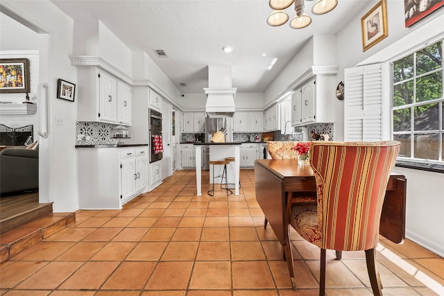 kitchen featuring white cabinets, a kitchen breakfast bar, light tile patterned floors, and backsplash