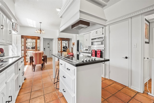 kitchen with a breakfast bar, an inviting chandelier, white cabinetry, a kitchen island, and stainless steel double oven