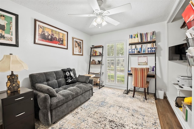 living room featuring hardwood / wood-style floors, ceiling fan, and a textured ceiling