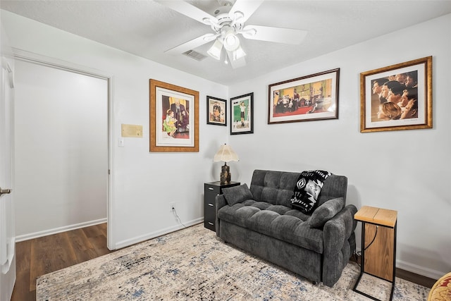 living room featuring ceiling fan, wood-type flooring, and a textured ceiling