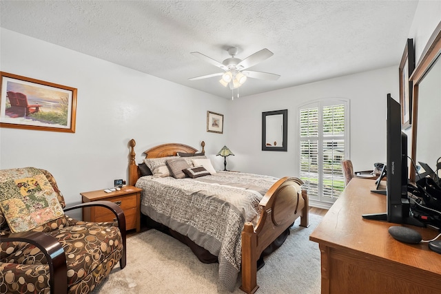 bedroom featuring ceiling fan, light colored carpet, and a textured ceiling