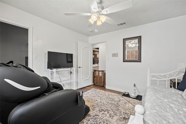 bedroom with ceiling fan, wood-type flooring, and a textured ceiling