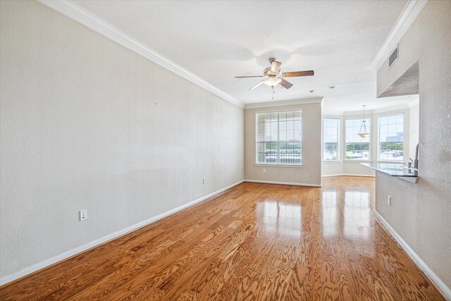 unfurnished room featuring hardwood / wood-style flooring, ornamental molding, and ceiling fan