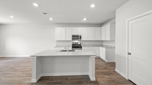 kitchen with appliances with stainless steel finishes, white cabinetry, and an island with sink