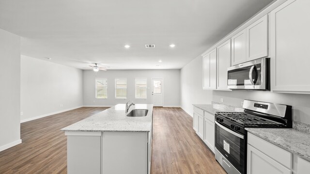 kitchen featuring ceiling fan, stainless steel appliances, white cabinets, light stone counters, and sink