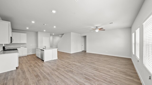 kitchen featuring white cabinets, stainless steel appliances, an island with sink, light hardwood / wood-style floors, and ceiling fan