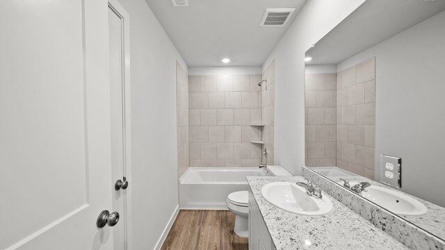 full bathroom with toilet, tiled shower / bath combo, wood-type flooring, and vanity