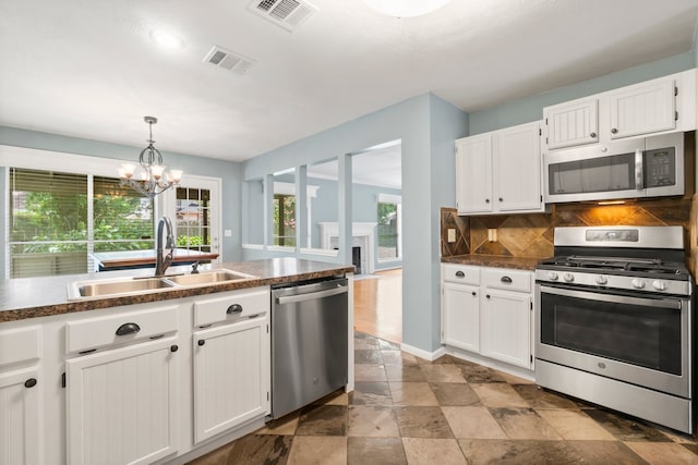 kitchen with white cabinets, stainless steel appliances, tasteful backsplash, sink, and light tile floors