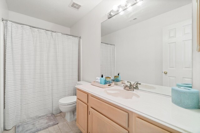 bathroom with tile floors, toilet, and vanity with extensive cabinet space