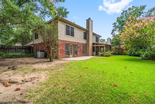 rear view of property with a yard, central AC unit, and a patio area