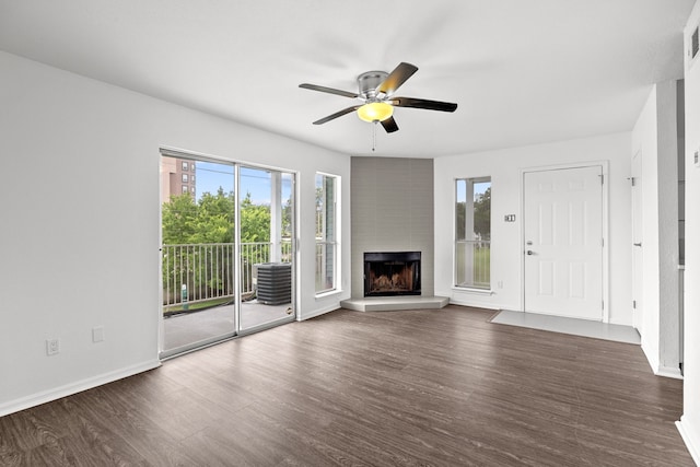 unfurnished living room with a large fireplace, ceiling fan, and dark wood-type flooring