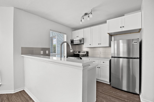 kitchen featuring kitchen peninsula, appliances with stainless steel finishes, backsplash, dark hardwood / wood-style floors, and white cabinetry