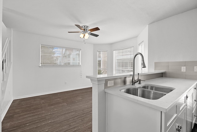 kitchen with dark wood-type flooring, white cabinets, sink, ceiling fan, and kitchen peninsula