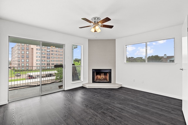 unfurnished living room with a fireplace, ceiling fan, and dark wood-type flooring