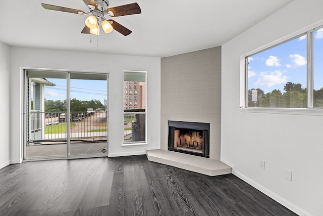 unfurnished living room with a wealth of natural light, a large fireplace, and dark wood-type flooring