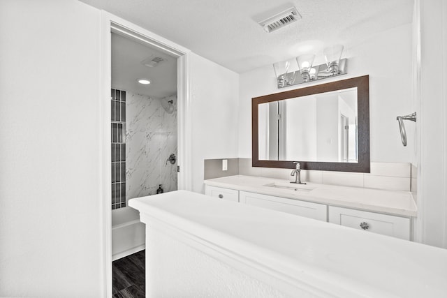 bathroom featuring hardwood / wood-style flooring, vanity, a tub to relax in, and a textured ceiling