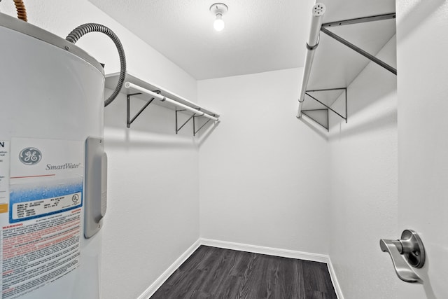 spacious closet featuring electric water heater and dark hardwood / wood-style flooring