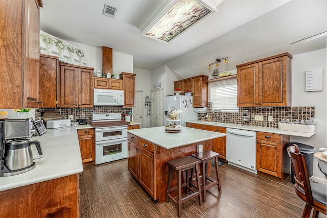 kitchen with decorative backsplash, a kitchen island, a kitchen breakfast bar, white appliances, and dark wood-type flooring