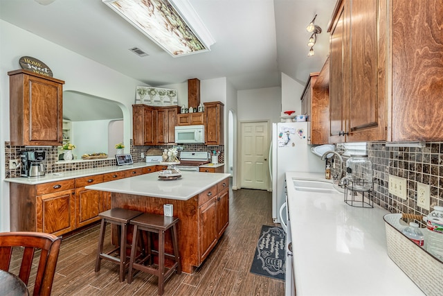 kitchen featuring a breakfast bar, backsplash, a center island, dark hardwood / wood-style floors, and stove