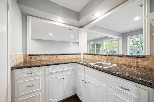 kitchen with white cabinetry, tasteful backsplash, dark stone counters, and sink