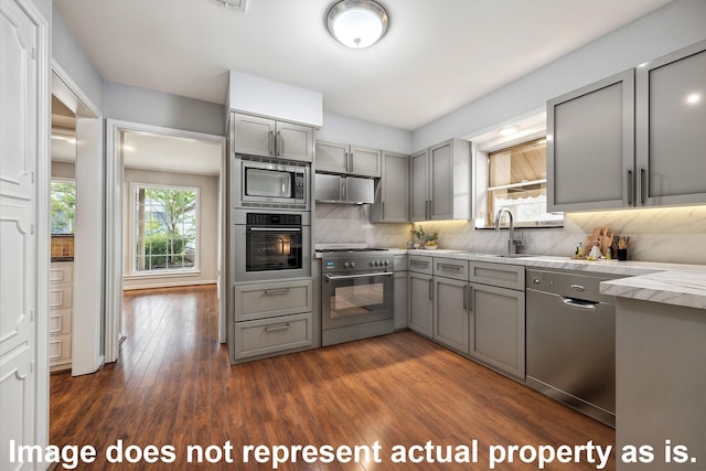 kitchen with stainless steel appliances, sink, backsplash, dark hardwood / wood-style floors, and gray cabinetry