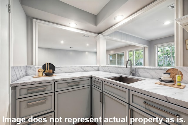 kitchen featuring light stone counters, sink, and gray cabinetry