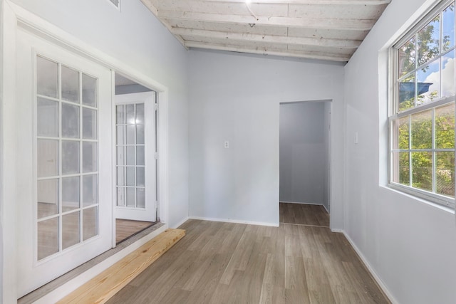 unfurnished room with hardwood / wood-style floors and vaulted ceiling with beams