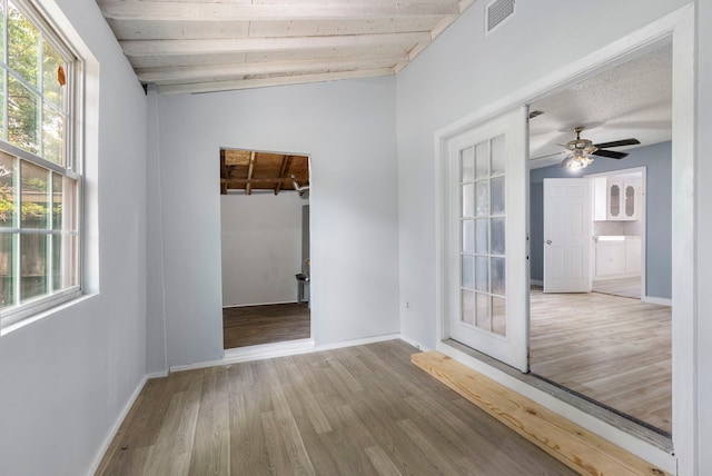 unfurnished room featuring french doors, light wood-type flooring, wood ceiling, ceiling fan, and lofted ceiling with beams