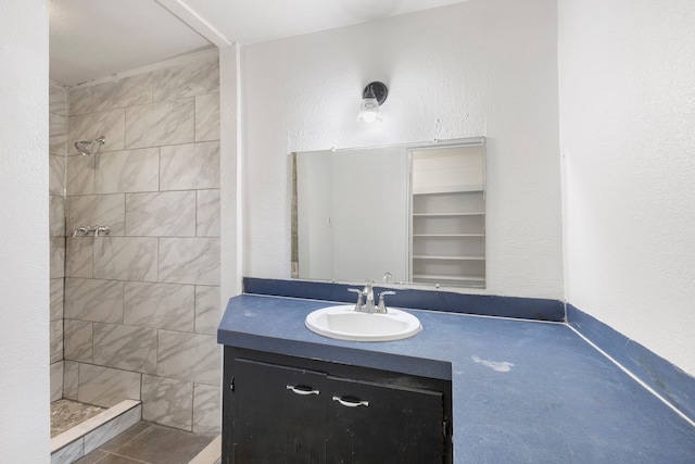 bathroom with a tile shower and vanity