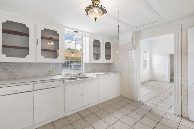 kitchen with white cabinets, tasteful backsplash, light tile patterned flooring, and sink