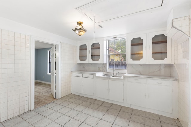 kitchen featuring decorative backsplash, white cabinetry, hanging light fixtures, and sink