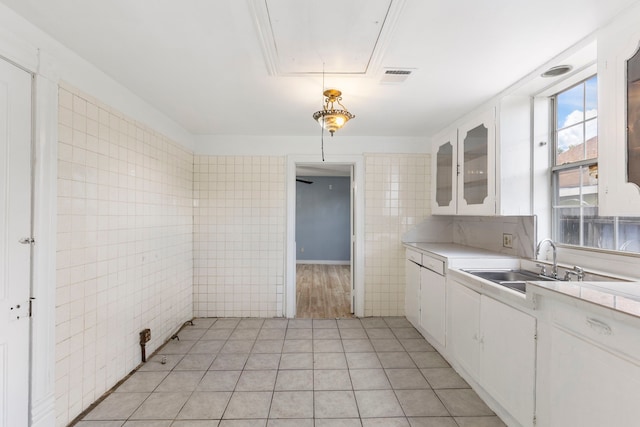 kitchen featuring light tile patterned flooring, white cabinetry, sink, and tile walls