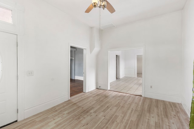 unfurnished room with a towering ceiling, light wood-type flooring, and ceiling fan