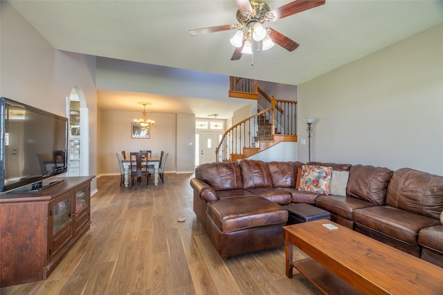 living room featuring ceiling fan with notable chandelier and light wood-type flooring