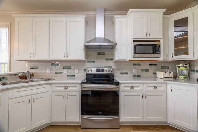 kitchen featuring decorative backsplash, sink, stainless steel appliances, and wall chimney range hood