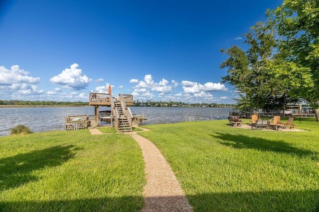 view of dock featuring a lawn, a deck with water view, and a fire pit