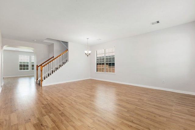 unfurnished room with baseboards, visible vents, light wood finished floors, an inviting chandelier, and stairs