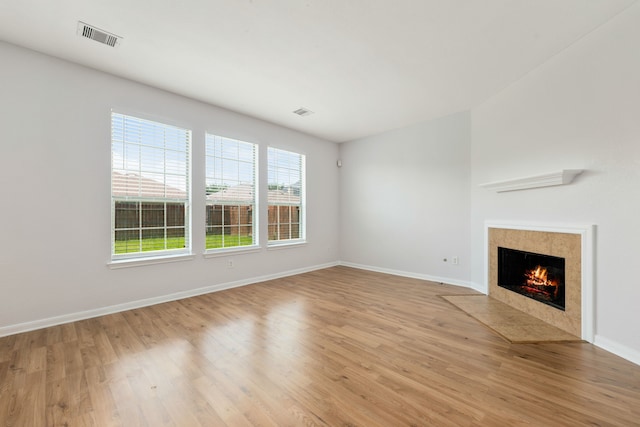 unfurnished living room featuring a fireplace, light wood-style floors, visible vents, and baseboards