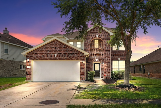 traditional-style house with a garage, a lawn, brick siding, and driveway