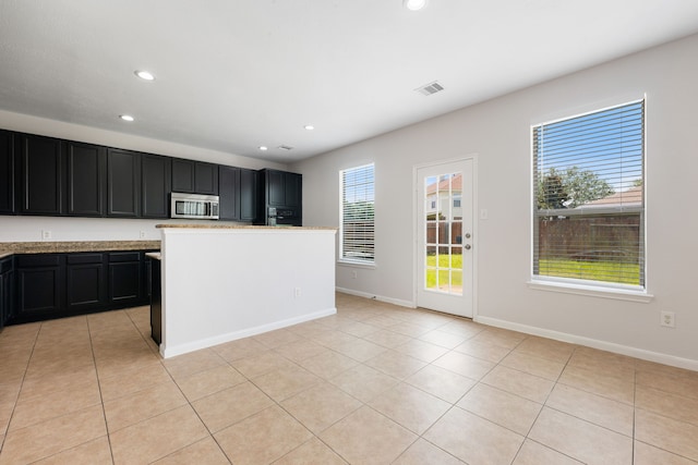 kitchen featuring light tile patterned floors, visible vents, recessed lighting, stainless steel microwave, and dark cabinets